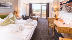A hotel room with a bed, a desk, a chair, a table, and a view of the outdoors. - Hotel Nesselwanger Hof (Nesselwang)