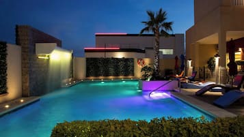 Una piscina de diseño moderno, rodeada por un área ajardinada con plantas y una palmera.