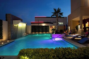 A swimming pool with a modern design, surrounded by a landscaped area with plants and a palm tree. - Four Points By Sheraton Queretaro Norte (Querétaro)