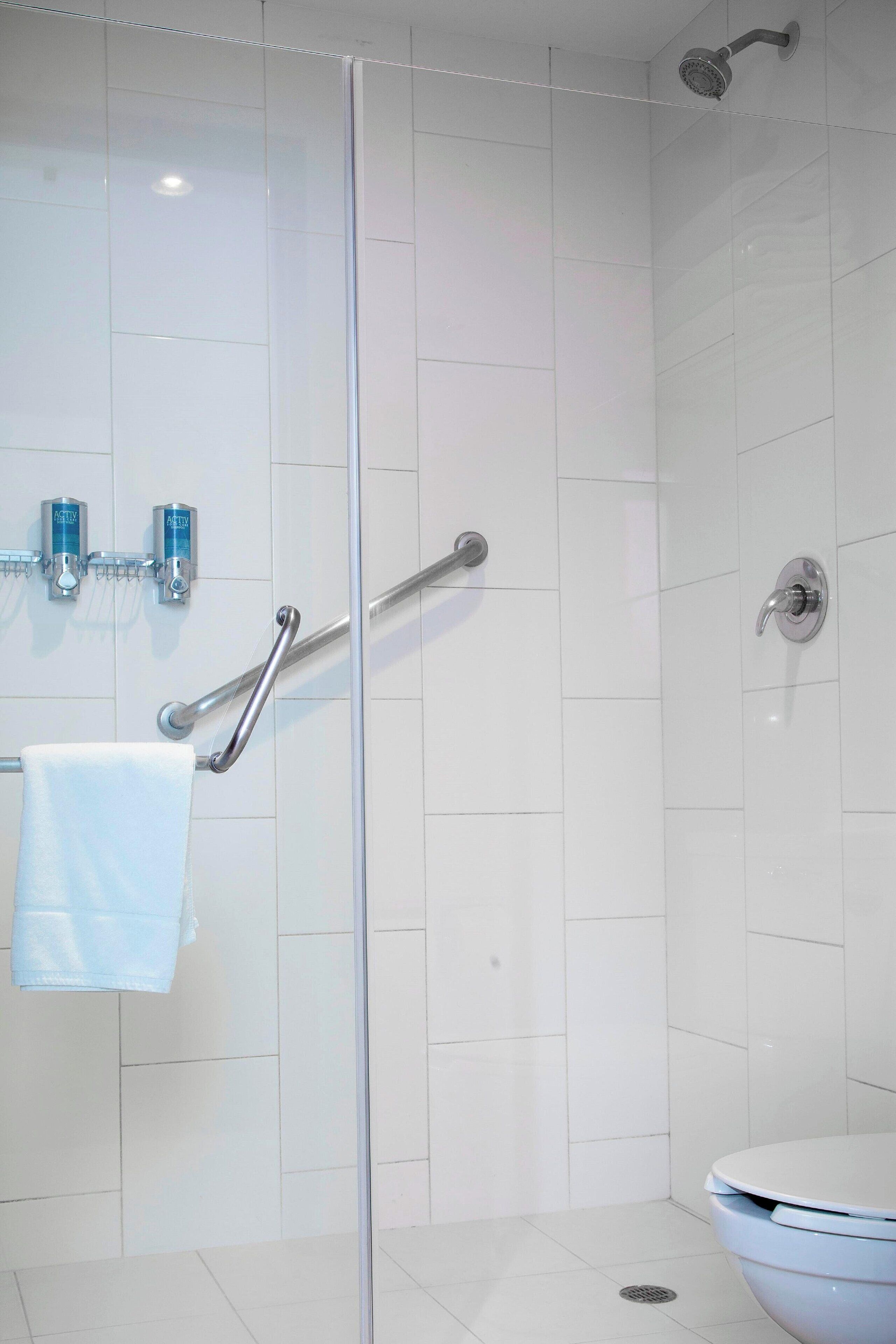 A modern bathroom with a glass shower enclosure, a white toilet, and a towel rack with a towel.