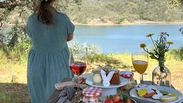 Une personne est assise à une table de pique-nique, avec vue sur un lac et des collines.