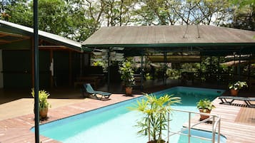 Relax by the pool surrounded by lush greenery and comfortable seating.
