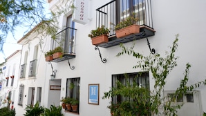 Un edificio con balcones decorados con plantas en macetas y un letrero que dice 'La Posada'.