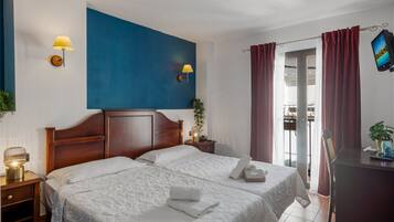 Habitación de hotel con una cama grande, dos lámparas de noche, un televisor de pantalla plana y vistas al exterior.