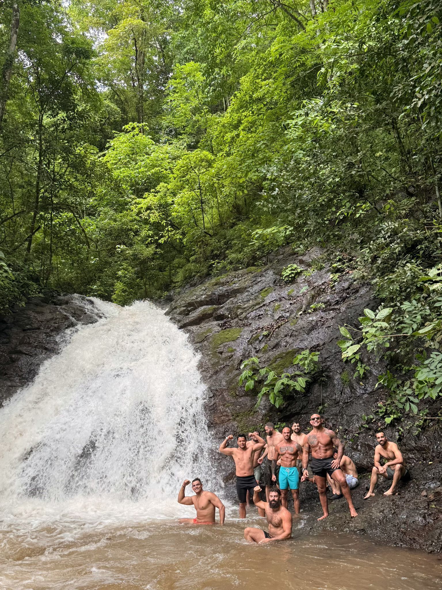 A group of people by a waterfall in a forested area.