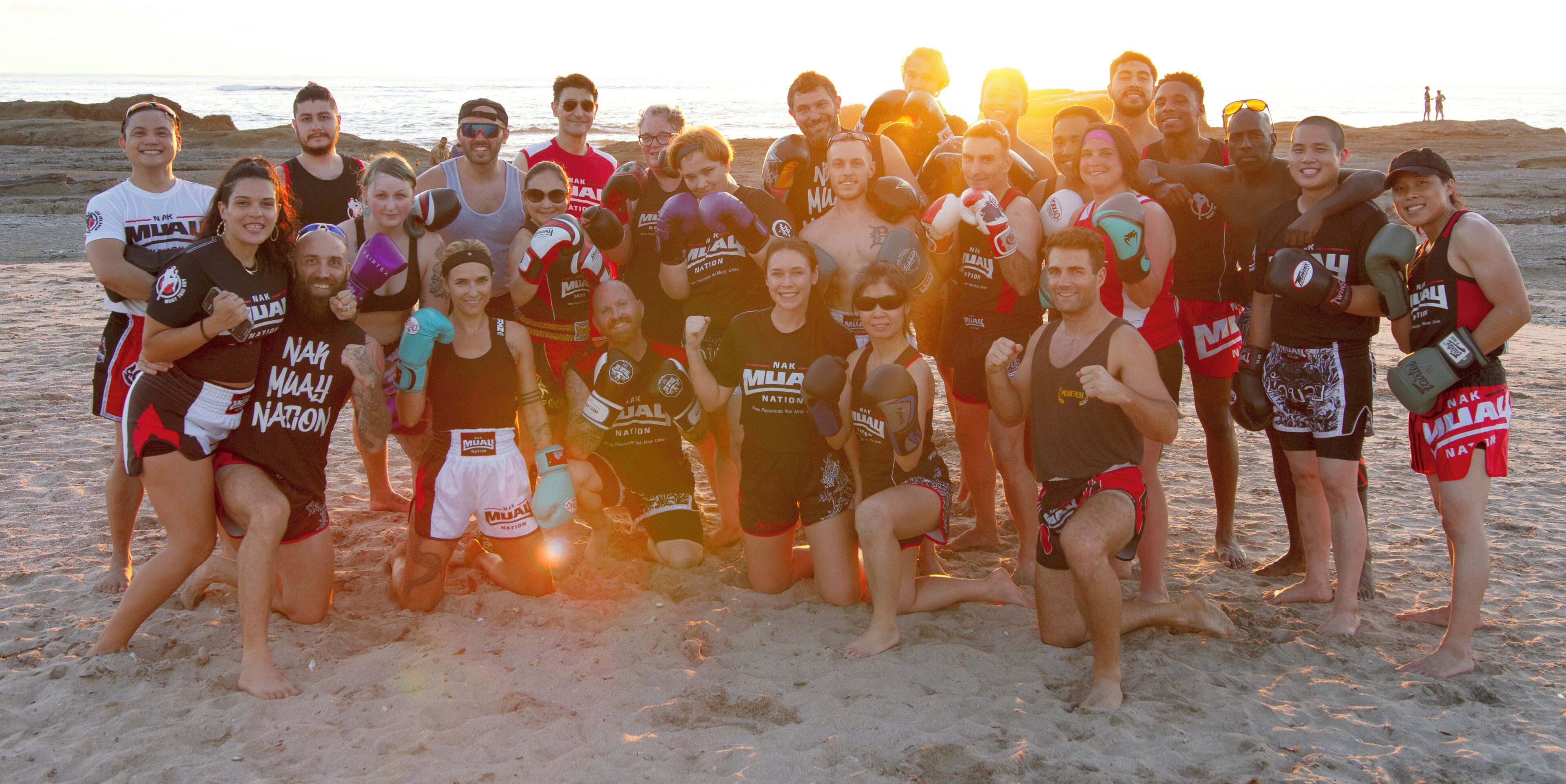 A group of people on a beach at sunset.