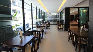 Un restaurant moderne avec de longues tables et des chaises, de grandes fenêtres et un intérieur épuré et lumineux.