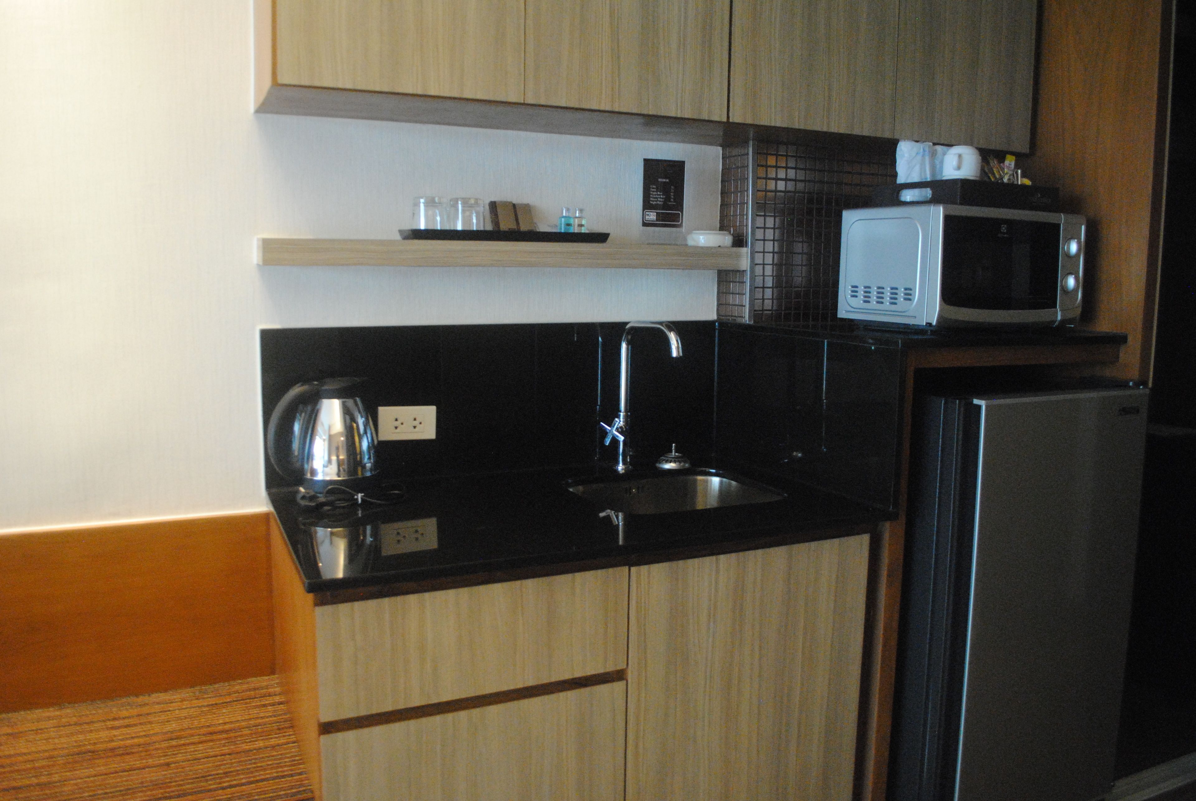 A kitchen with a black countertop, stainless steel sink, and a microwave.