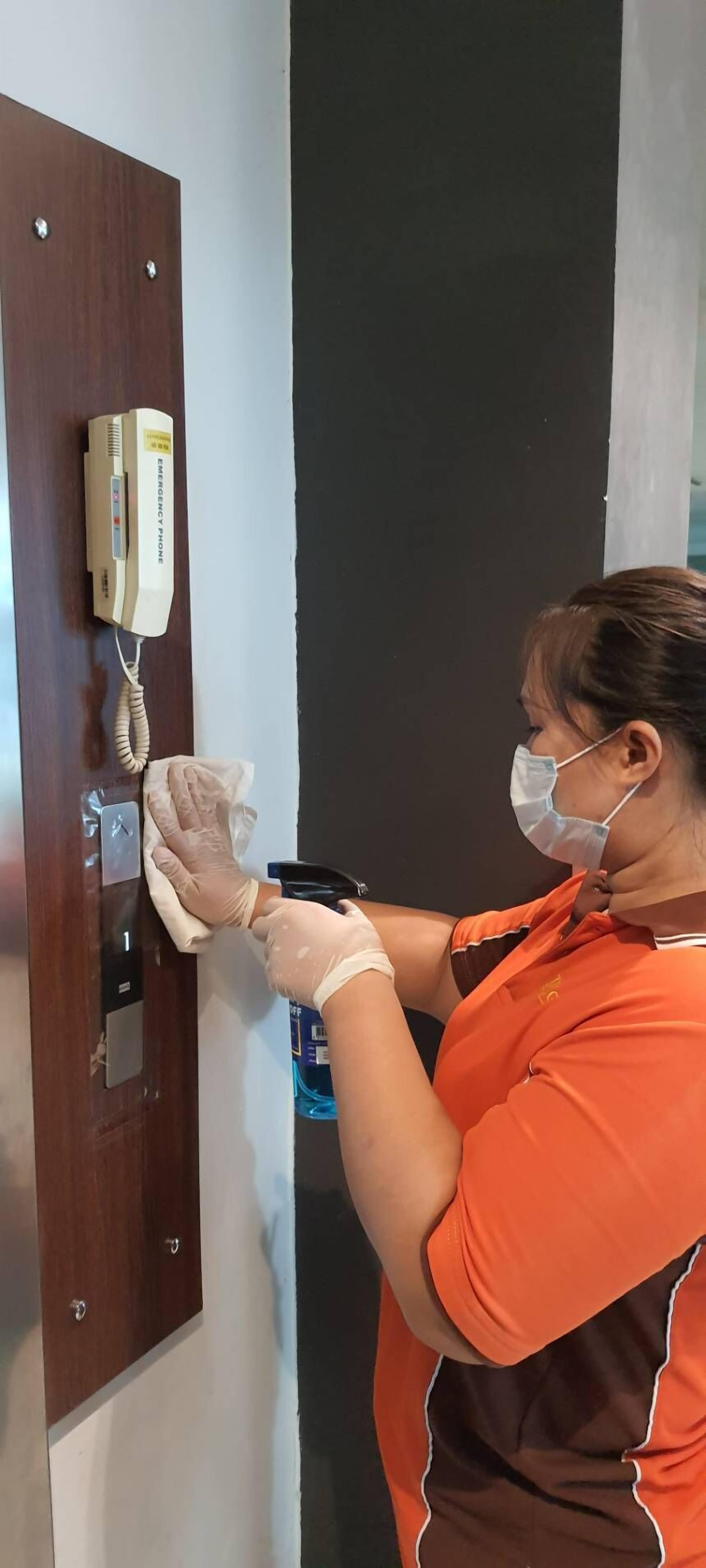 A person cleaning a wooden door with a cloth and a spray bottle.