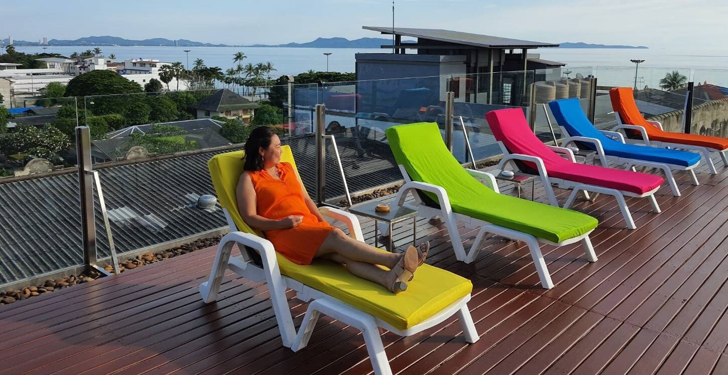 A deck with multiple sun loungers and a clear view of the sea and distant mountains.