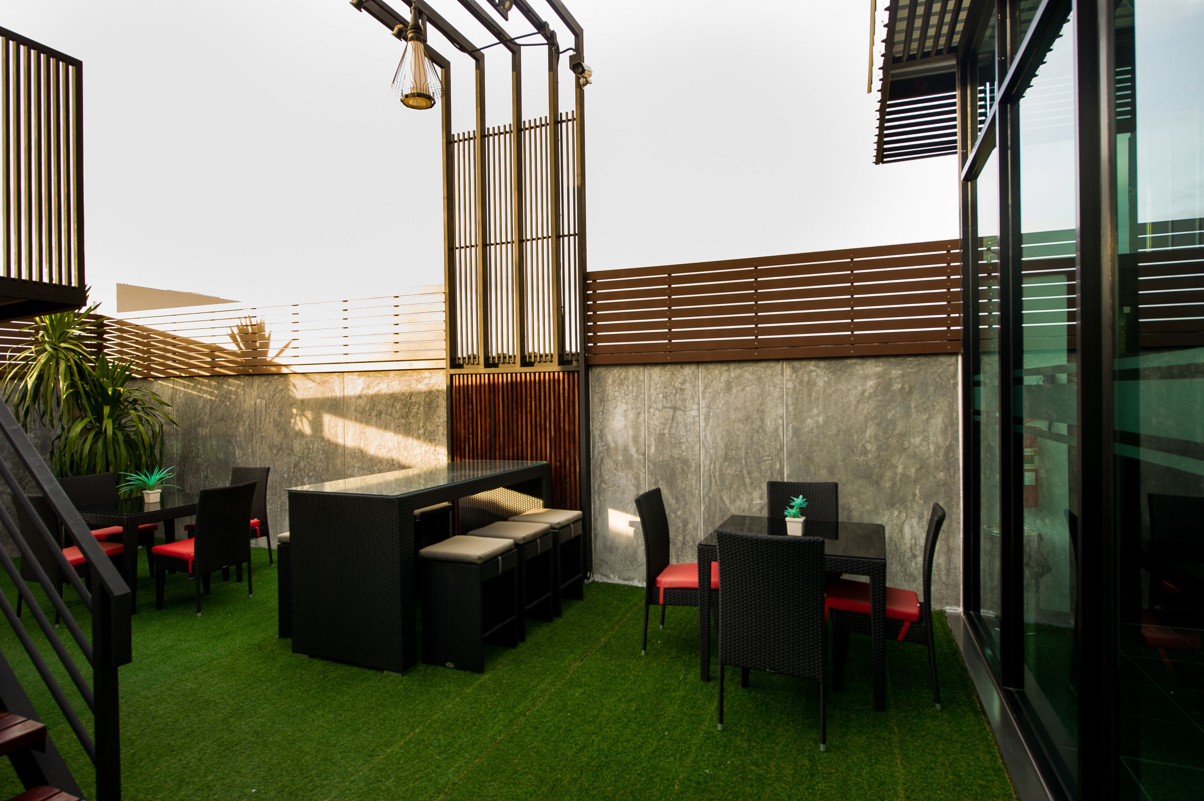 A rooftop terrace with artificial grass, outdoor furniture, and a view of the city skyline.