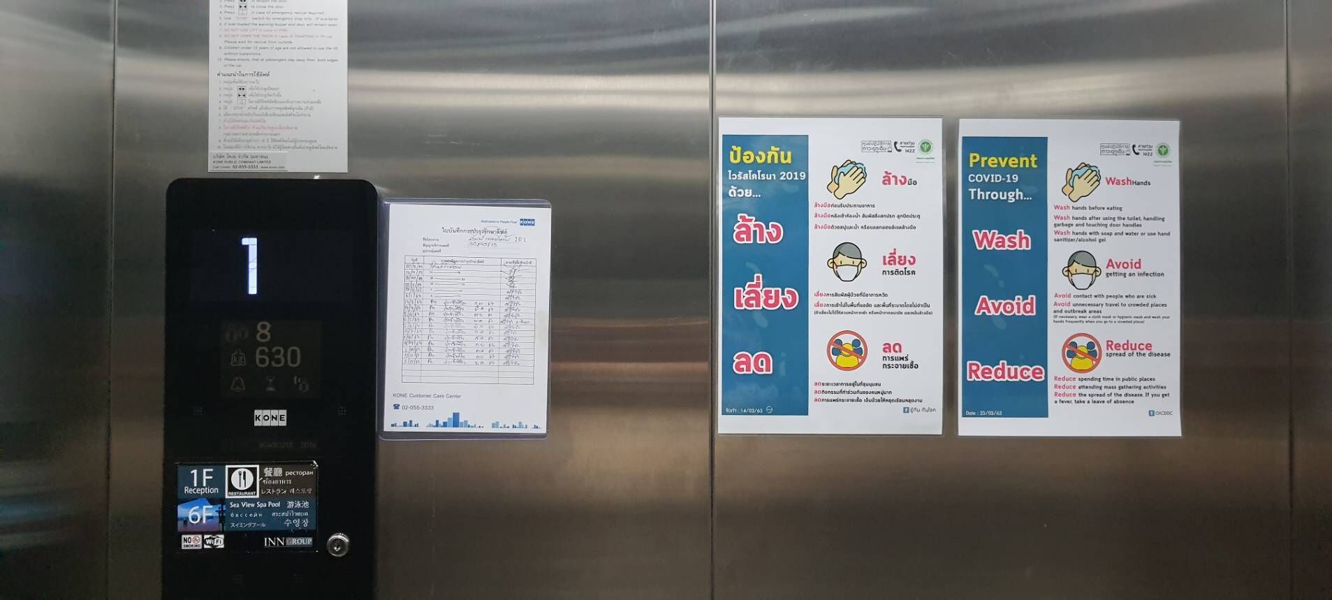 Ein Aufzug mit digitaler Anzeige, die die Etagen 1 und 8 zeigt, und einem Schild mit Corona-Präventionshinweisen.