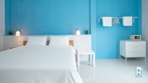 A modern hotel room with a large bed, white furniture, and a blue accent wall. - Ruk Cozy Khao Lak (Takua Pa)