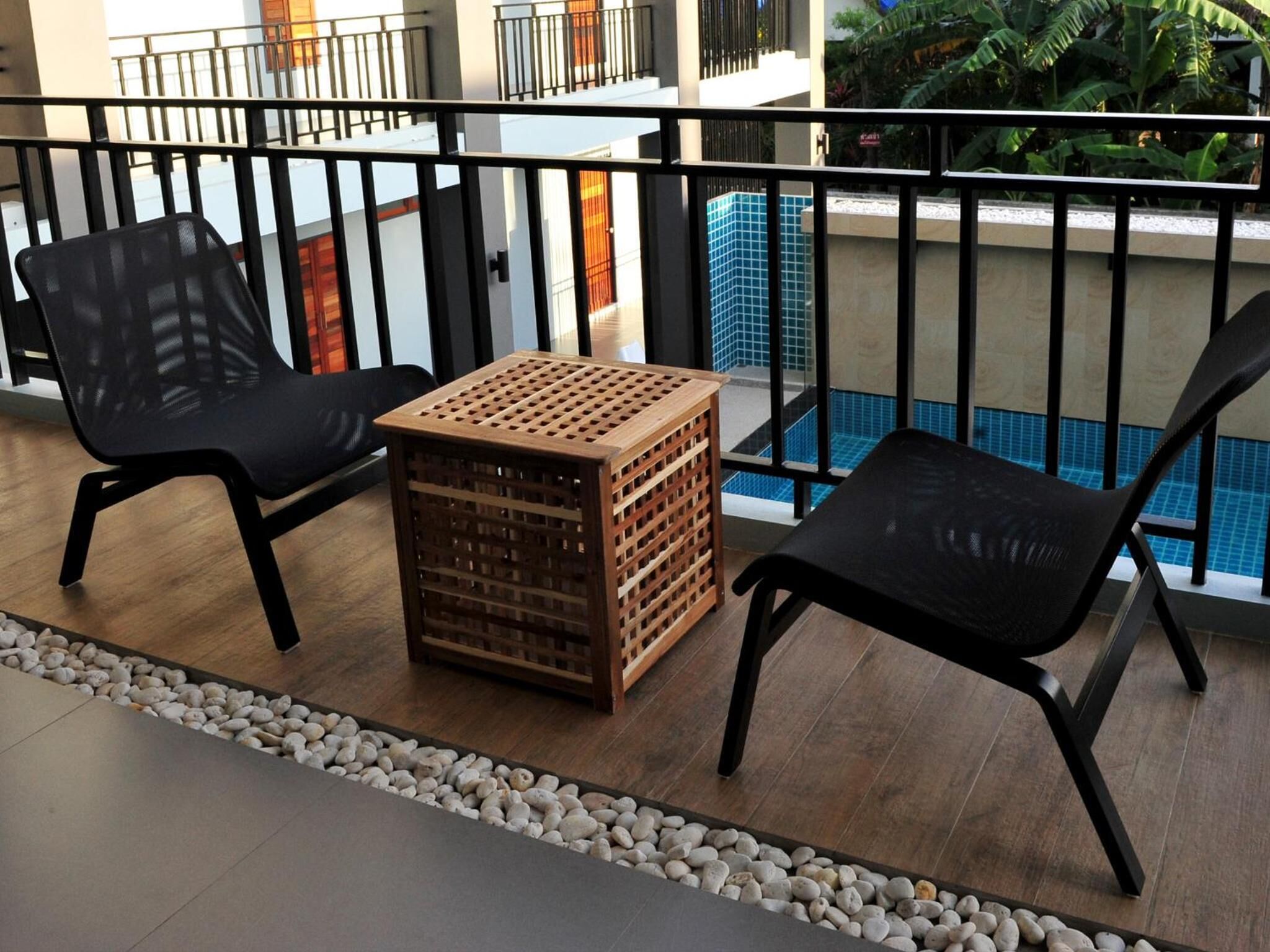 A balcony with two black chairs, a wooden crate, and a small table.