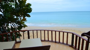 Vista sulla spiaggia da un balcone con ringhiera in legno, un tavolo e sedie.