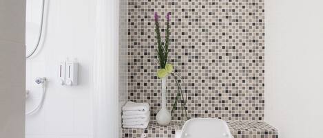 A modern bathroom with a shower, toilet, and a tiled backsplash.