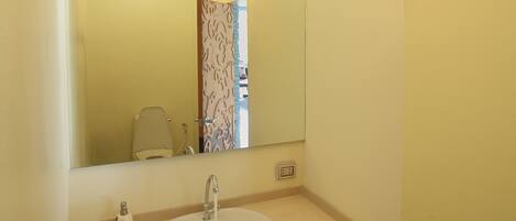 Un baño con lavamanos, espejo, candelabro y baldosas de suelo estampadas.