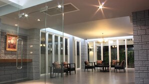 Un interior moderno con paredes de vidrio, un muro decorativo de piedra y una zona de estar con sillones acolchados.