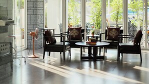 Una habitación amplia con diseño moderno, que cuenta con un ventanal grande, una araña y una zona de estar con una mesa y sillas.
