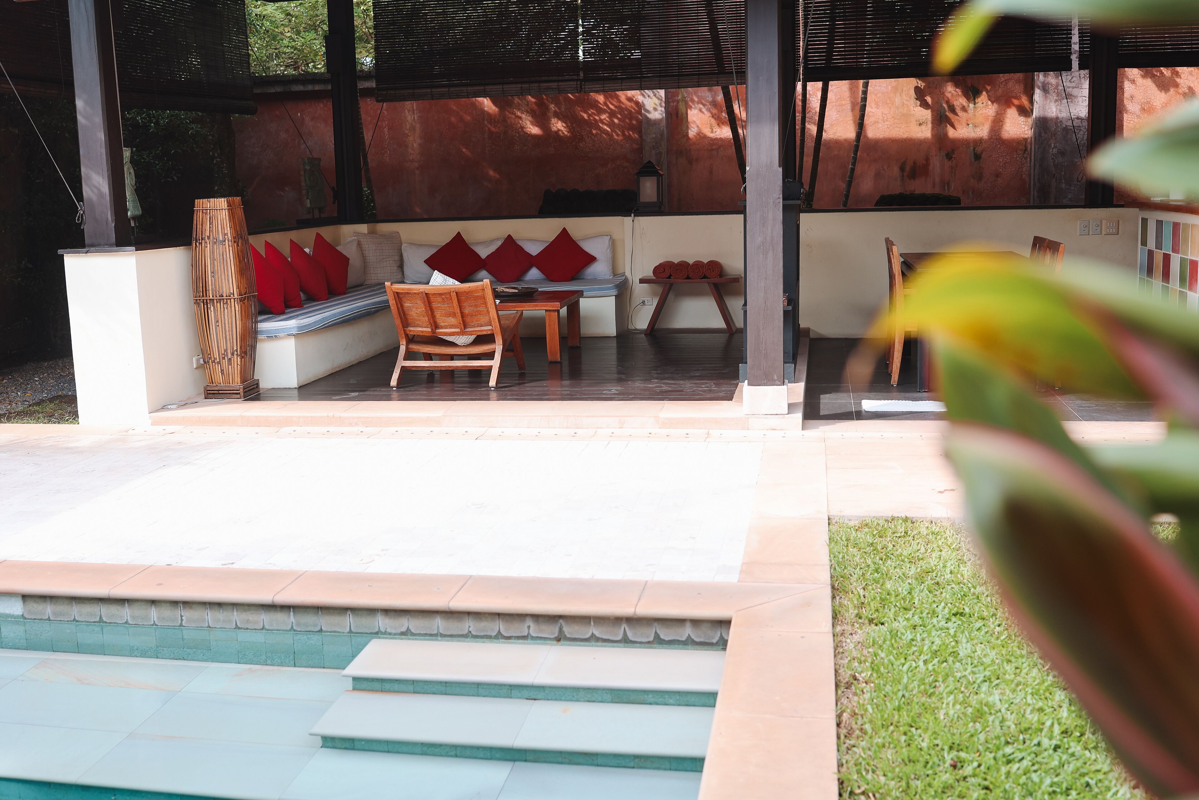 A covered outdoor seating area with a sofa, chairs, and a table.