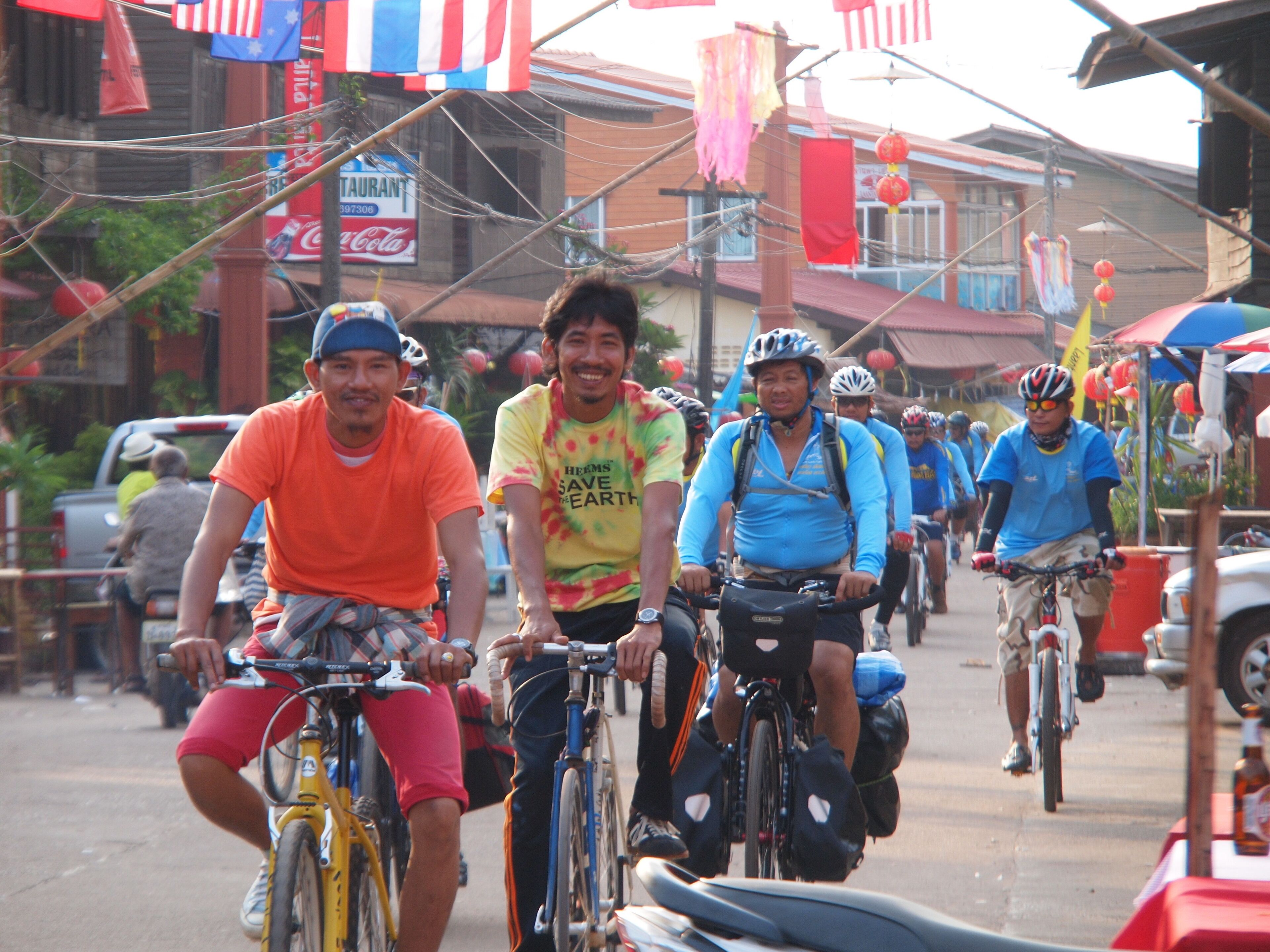 Un grupo de ciclistas en una calle con edificios y un letrero de restaurante al fondo.