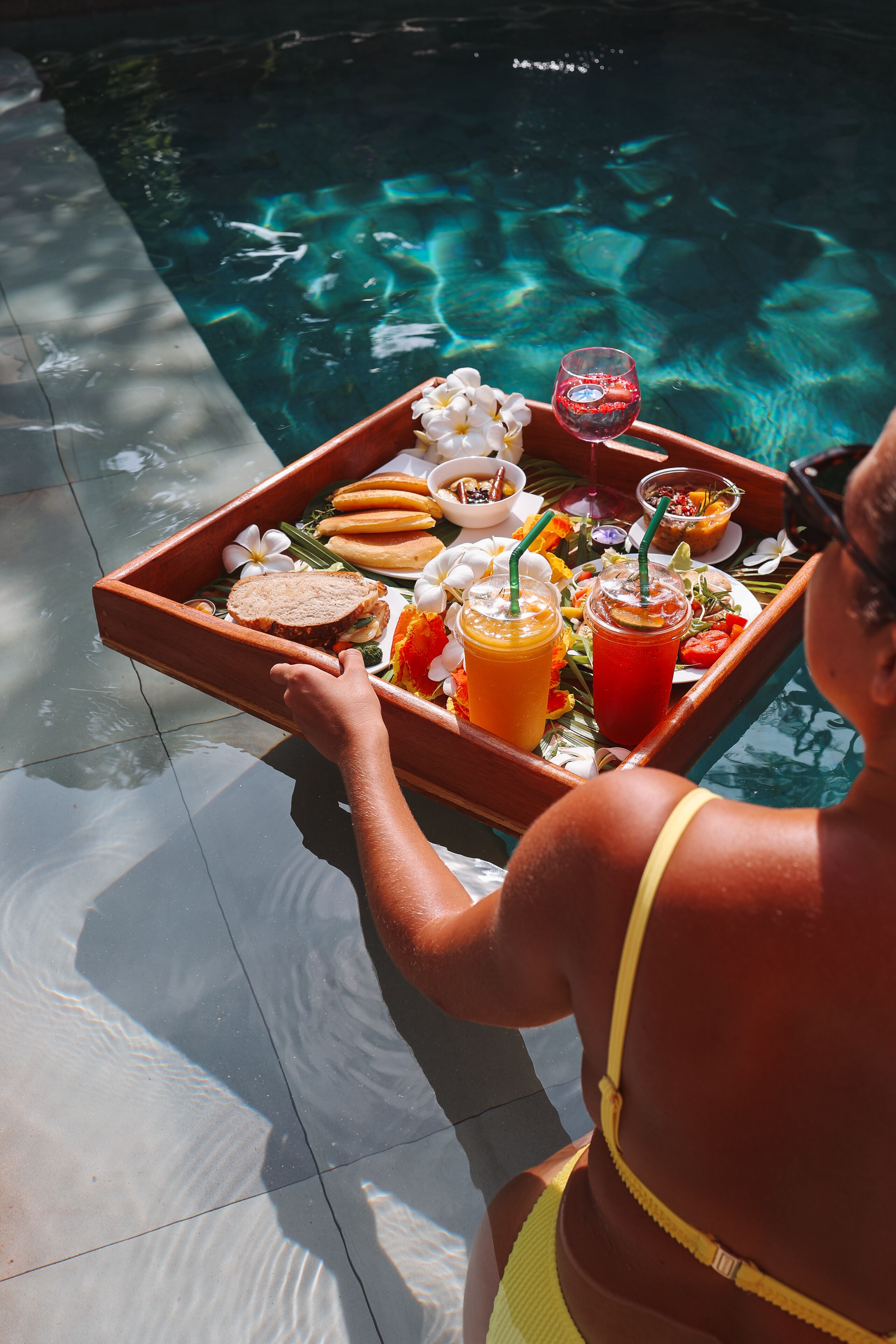 A tray with food and drinks by a pool.