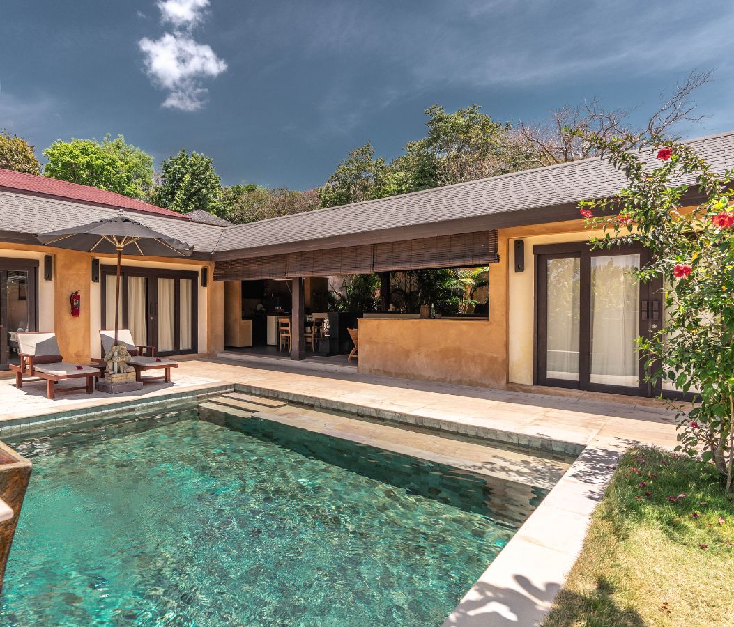 A modern hotel with a swimming pool, outdoor seating, and a covered patio area.
