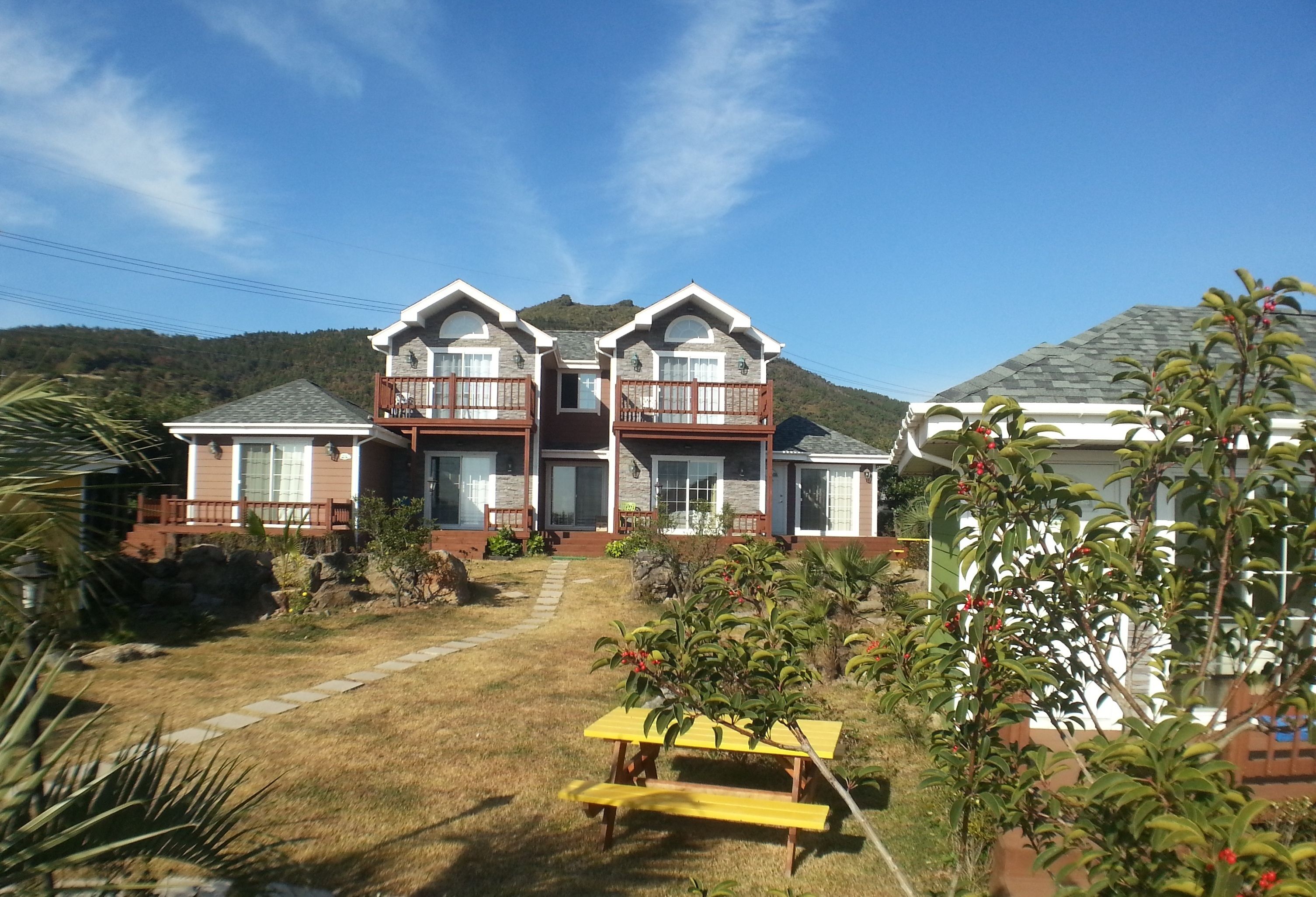 A two-story house with a front porch, a small garden, and a picnic table.