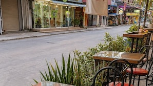 Outdoor seating with glass tables and red cushioned chairs, surrounded by potted plants. - Max Residence (Pattaya)