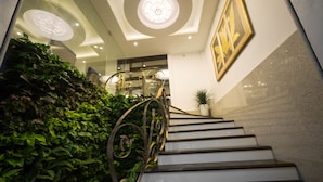 Eine Treppe mit Metallgeländer, umgeben von üppigem Grün und einem Blumentopf am oberen Ende.