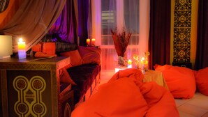 Een gezellige slaapkamer met een hemelbed, meerdere kaarsen en oranje beddengoed.
