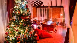 Een gezellige kamer met een grote kerstboom, een eettafel en een comfortabele zithoek.