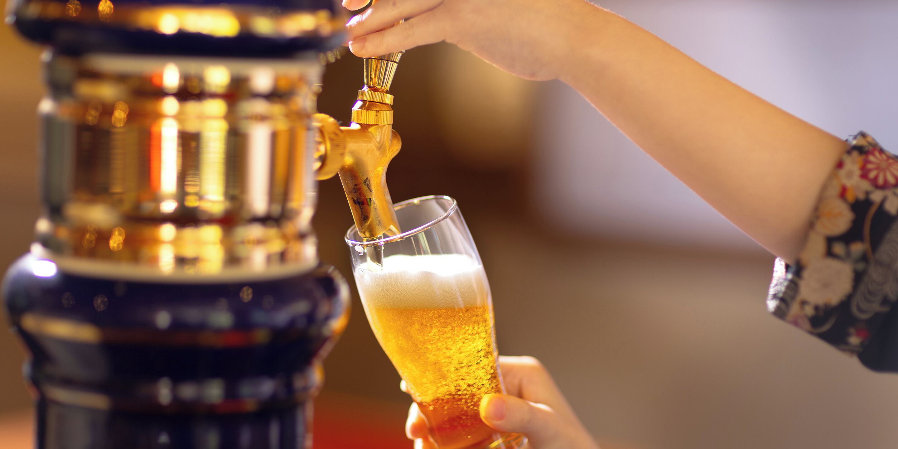Uma mão servindo cerveja de uma torneira em um copo.
