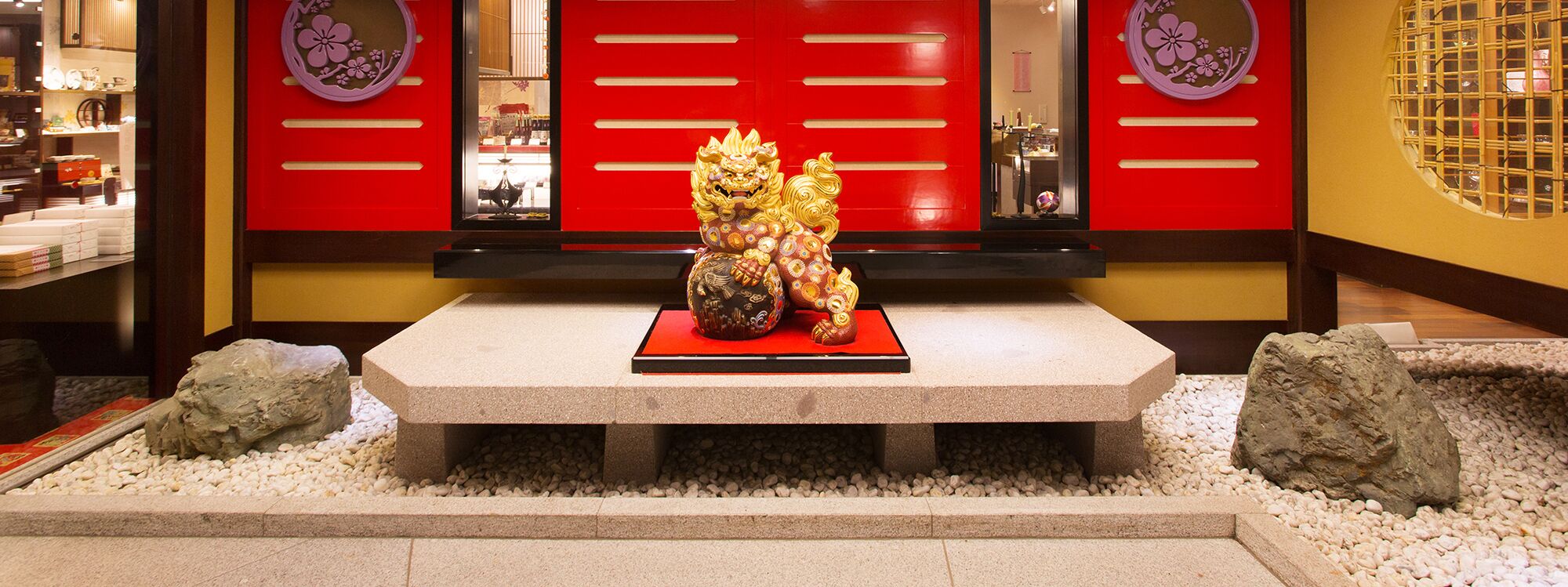 A traditional Chinese lion statue in a courtyard with red doors and decorative panels.