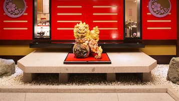 Eine traditionelle chinesische Löwenstatue in einem Innenhof mit roten Türen und dekorativen Verzierungen.