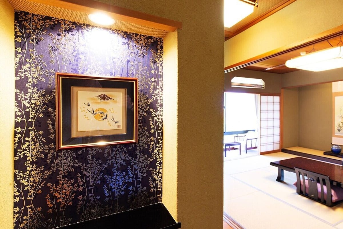 A traditional Japanese room with tatami flooring, a low table, and a framed artwork on the wall.