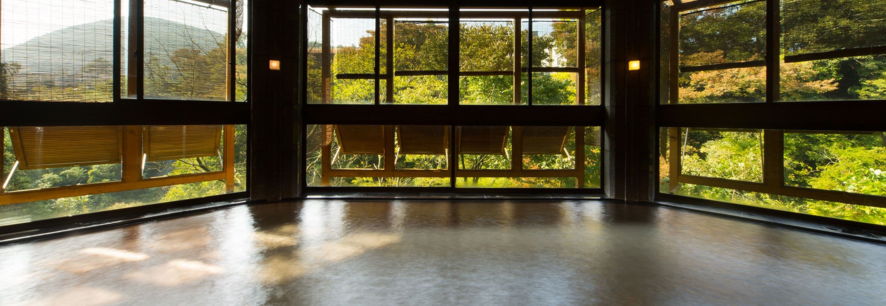 A spacious room with large windows offering a view of trees and a building.