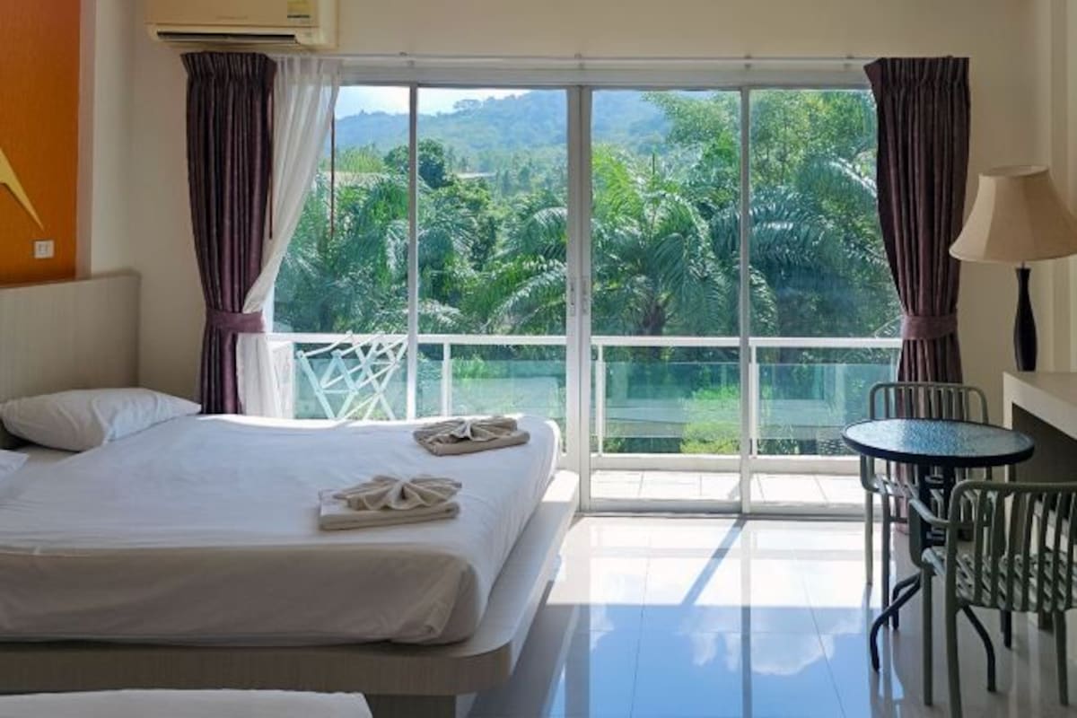 Una habitación de hotel con cama, mesa y vistas a zonas verdes.