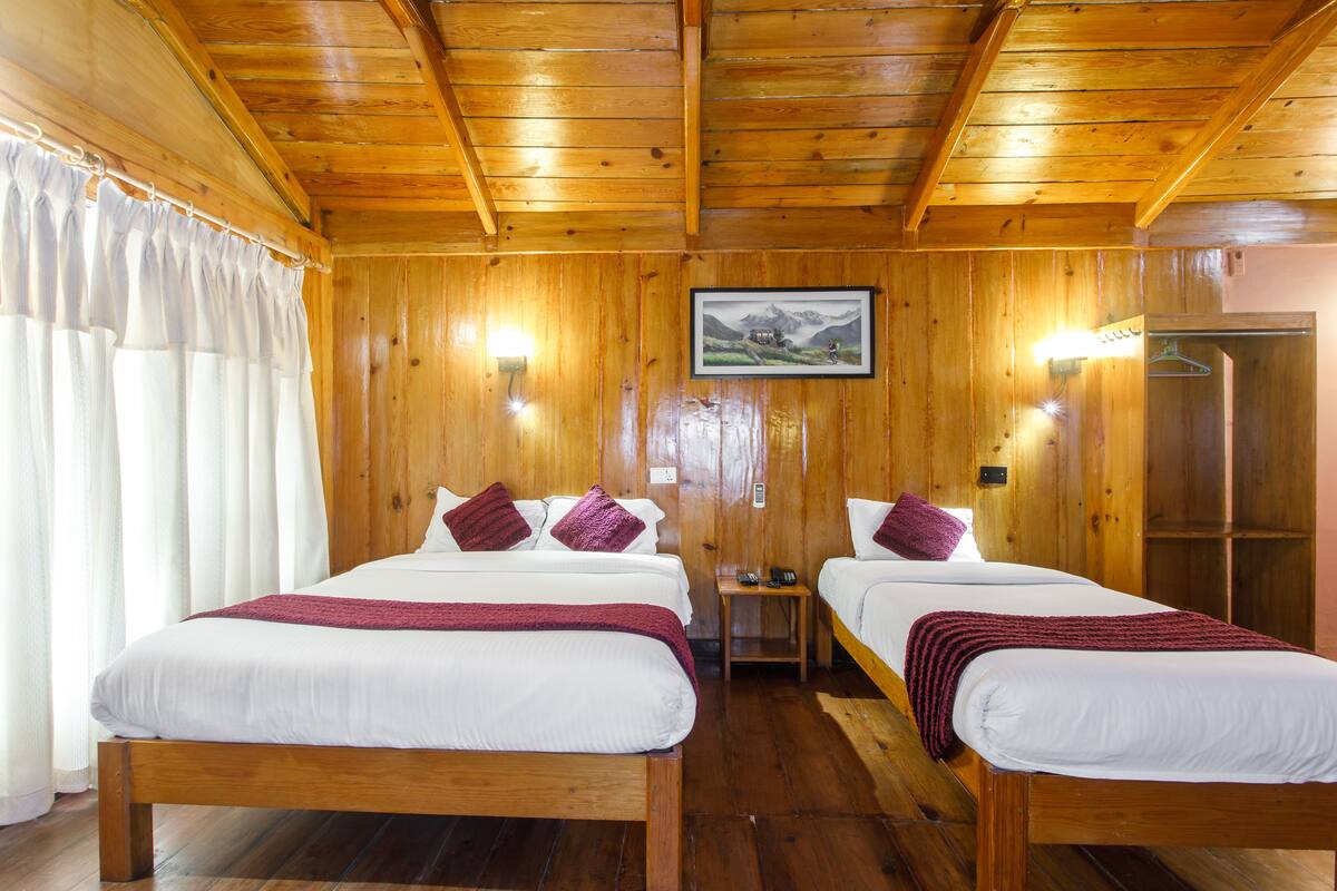 A wooden room with two beds, a small table, and a framed picture on the wall.