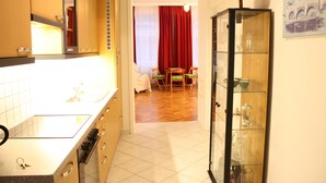 A kitchen with a stove, oven, and cabinets, leading to a dining area with a table and chairs. - GoVienna Homelike City Apartment (Vienna)