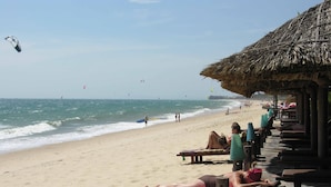 Una playa con tumbonas y una estructura de techo de paja.
