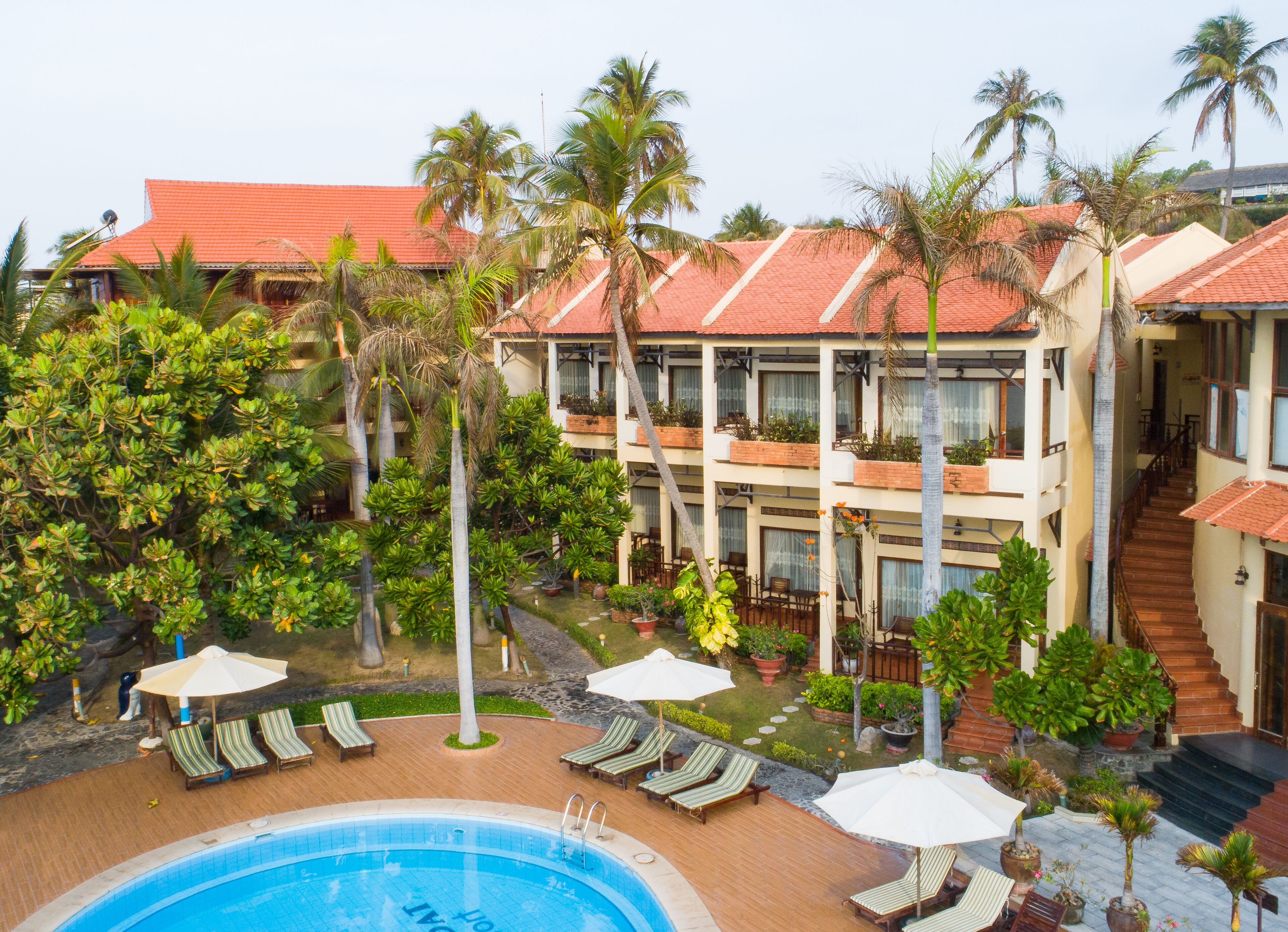 Ein Hotel mit Swimmingpool, Liegestühlen und Palmen.