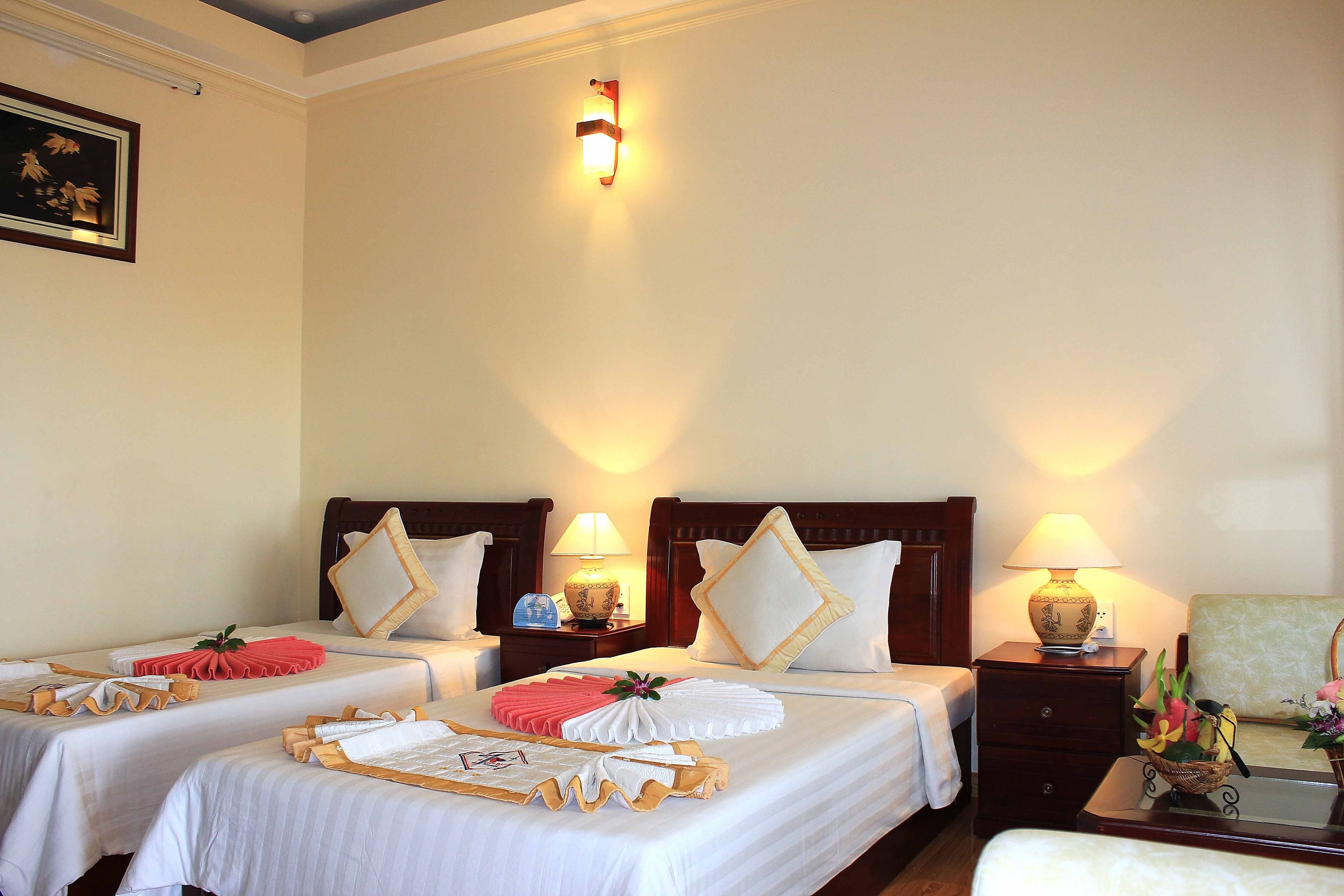 Una habitación de hotel con dos camas, cada una con una almohada y una mesita de noche con lámpara.
