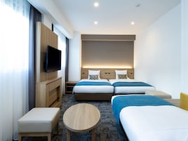A hotel room with two beds, a TV, a small table, and a sofa.