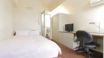 Ein Hotelzimmer mit Bett, Schreibtisch mit Computer, Stuhl und Fernseher.
