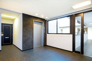 A modern hallway with a dark door, a light wall, and a large window.