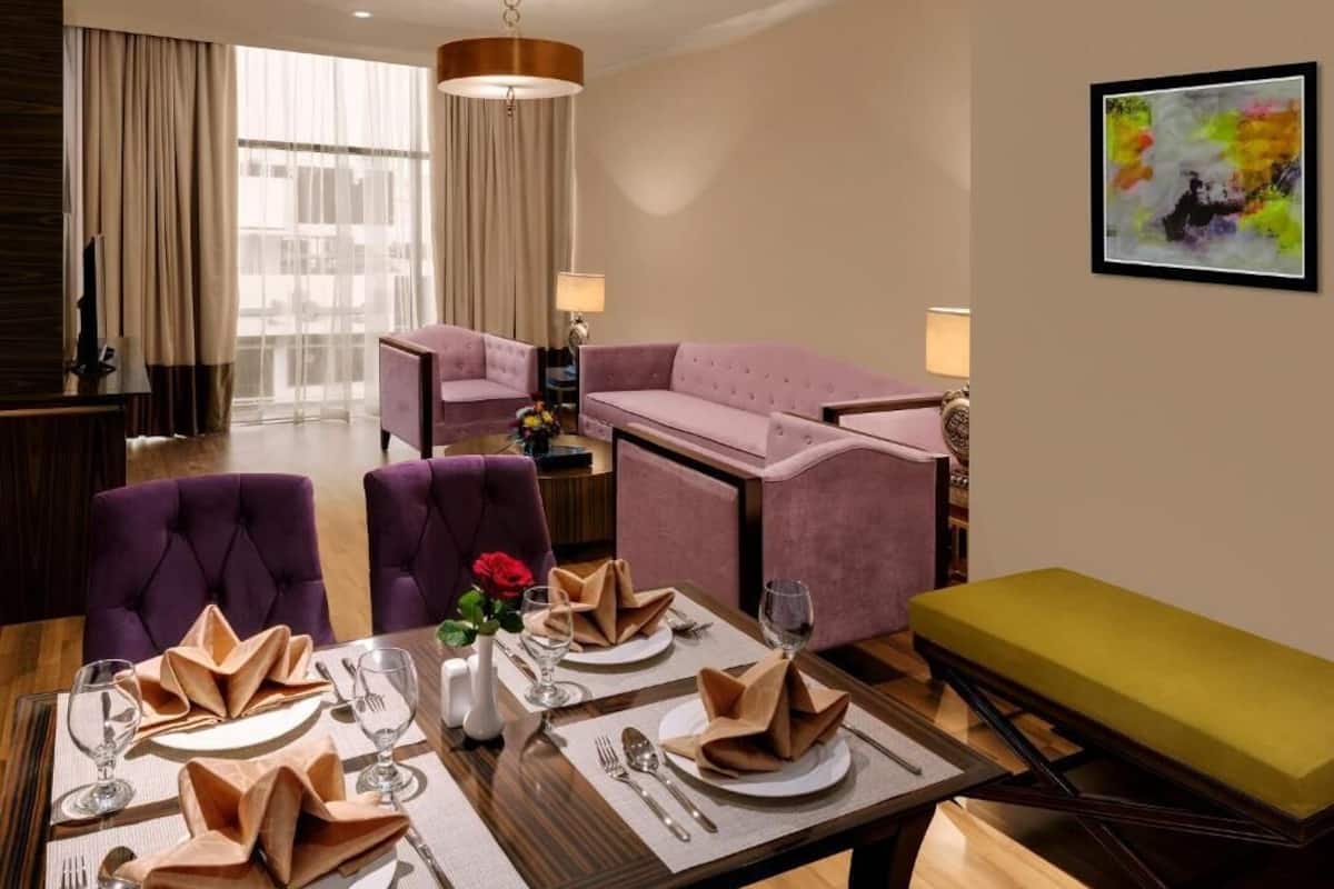 Une chambre d’hôtel avec un coin repas, un canapé et un tableau au mur.
