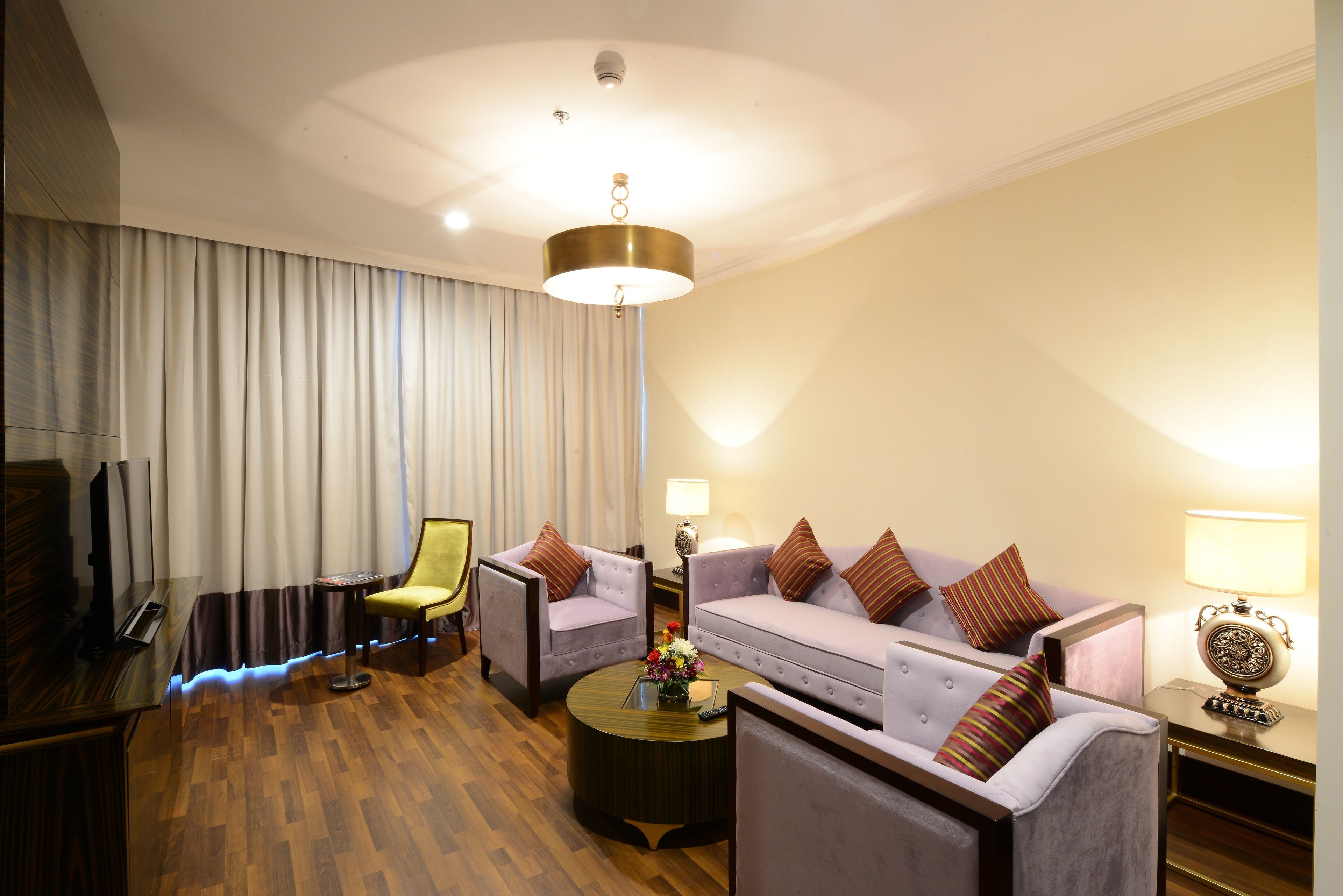 Una habitación de hotel con un piano, dos sillones, un sofá, una mesita de centro y una lámpara.