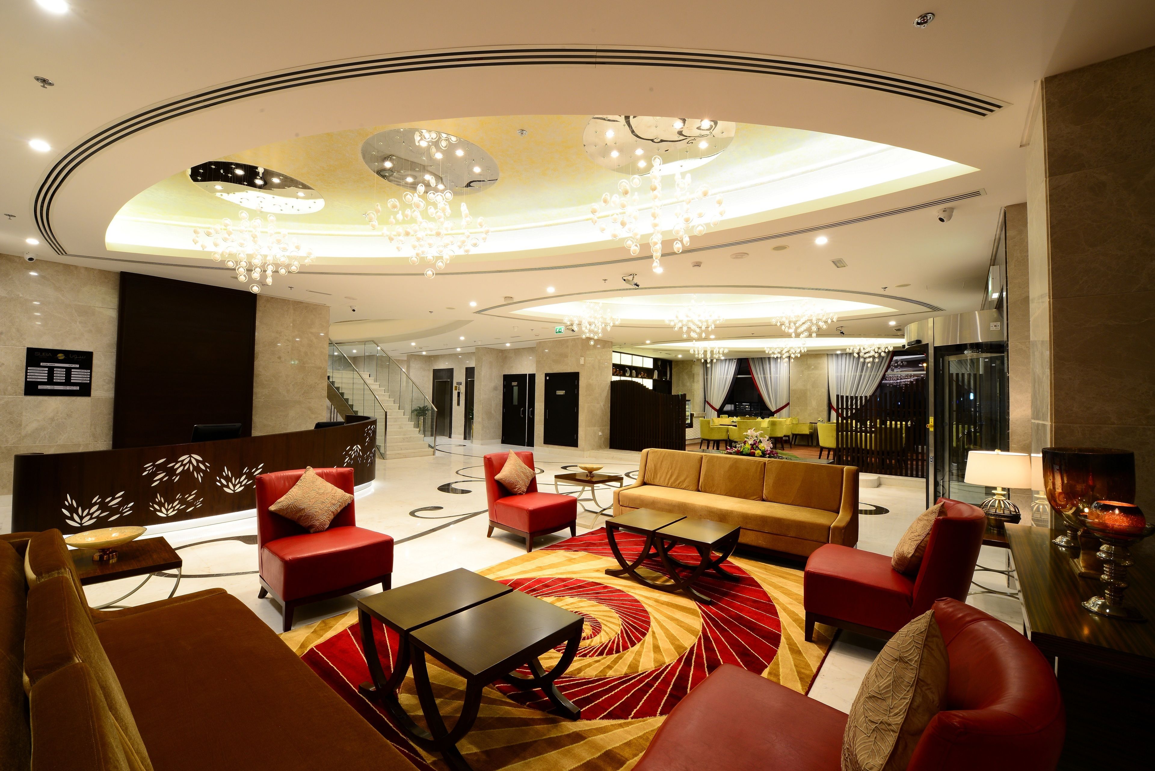 A modern lobby with a red and gold carpet, leather seating, and a chandelier.