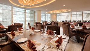 A dining area with tables set for service, large windows, and a modern chandelier. - Landmark Premier Hotel (Dubai)